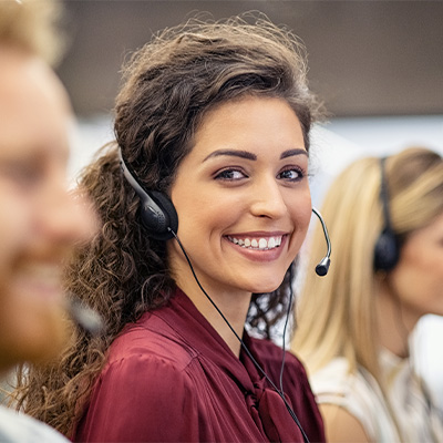 Une téléconseillère souriante dans un call center nous regarde