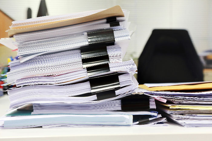 Piles de documents administratifs posées sur un bureau